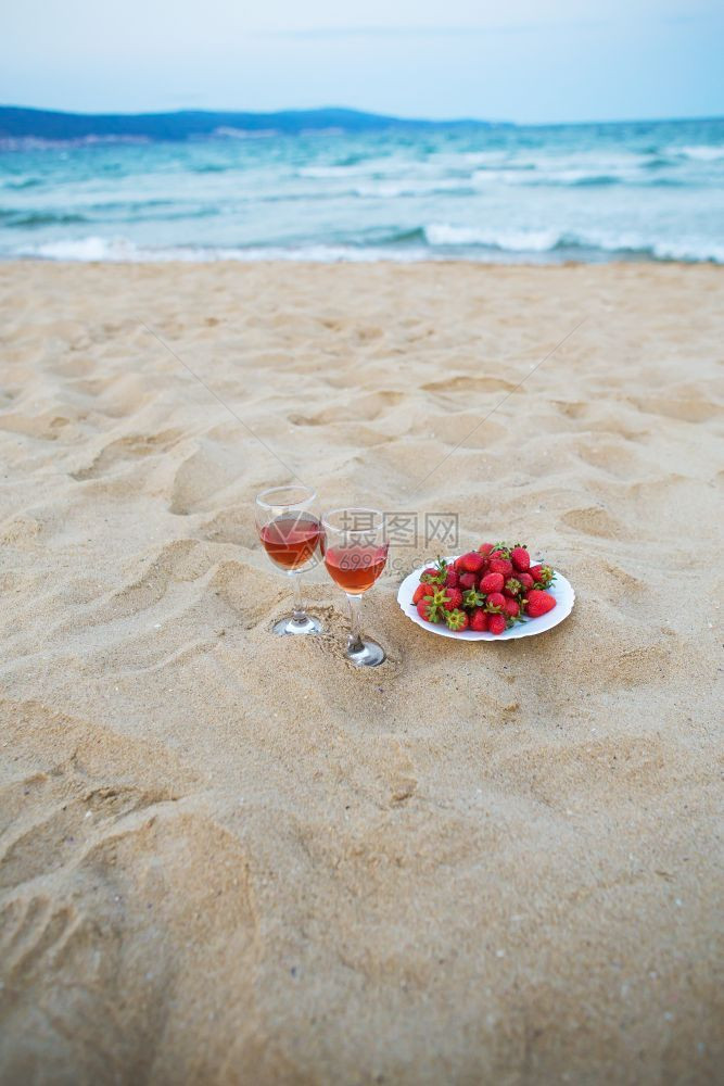 两杯酒和一盘草莓在沙滩上海边野餐两杯酒和一盘草莓在沙滩上海边野餐假期鸡尾酒新鲜的图片