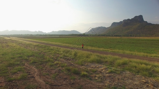 健康夏天线山区日落时妇女在农村公路上运行的空中景象图片