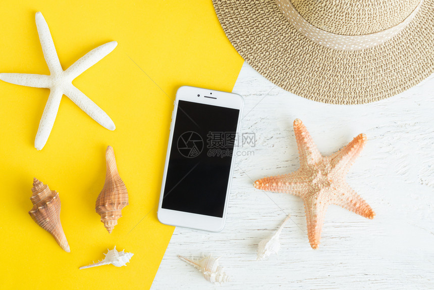 地面帽子黄纸和白木板上的黄纸和白木桌上面的Top视图为暑假提供平面照相智能手机和贝壳放松图片