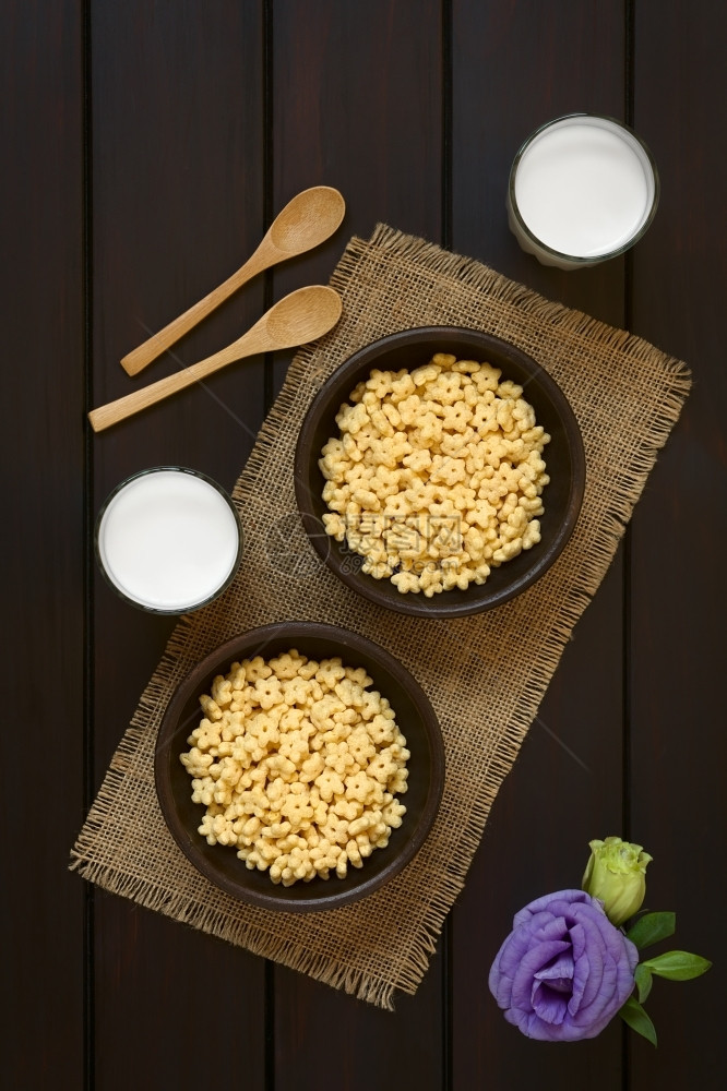 两碗有蜜味早餐口的麦片两碗生锈的马加牛奶杯和侧边木勺子用自然光照在黑木头上一顿饭甜的谷物图片
