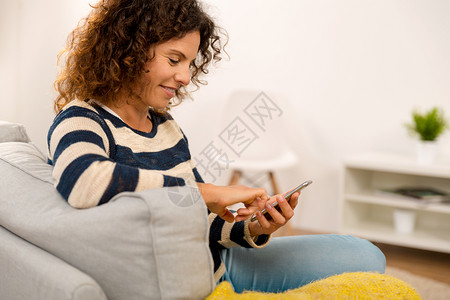 休息坐在沙发上短信的漂亮女人在沙发上写短信无线的活图片