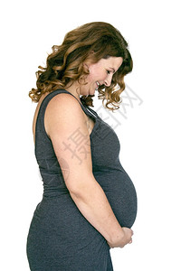 出生年轻的母将手放在肚子上的成年怀孕妇女图片