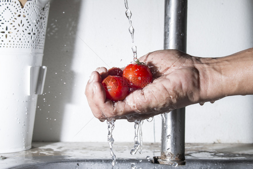 樱桃雄手的番茄与下水清洁食物红色的液体图片