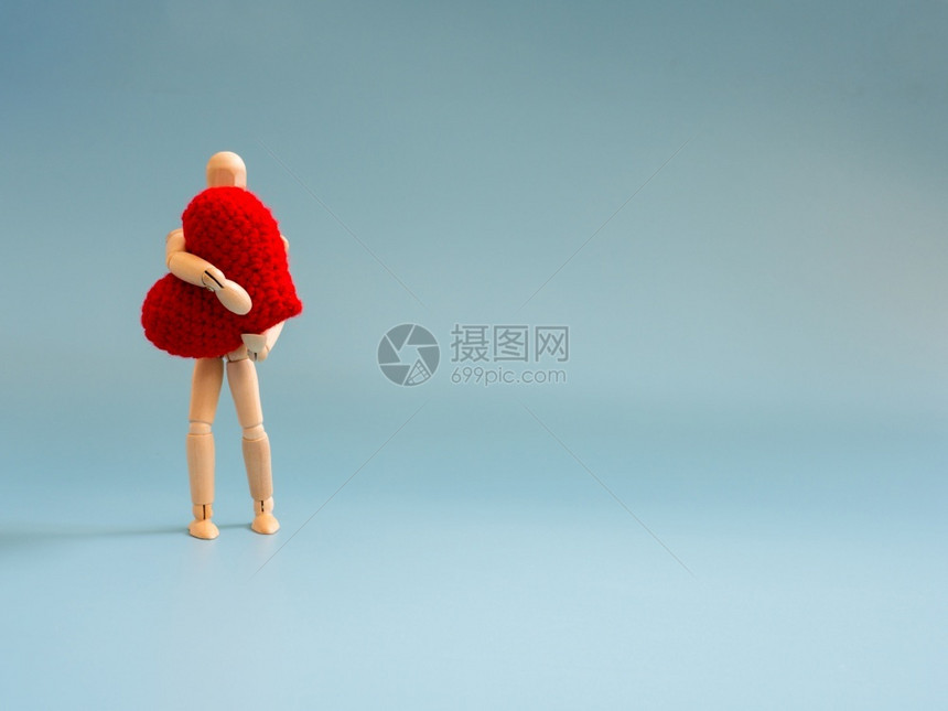 Wooden木偶站立在蓝屏背景上握着红心木棍偶持着爱与关的心照顾与爱的概念身体男人红色的图片