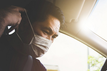司机在车里戴着外科口罩阳光流行病感染图片