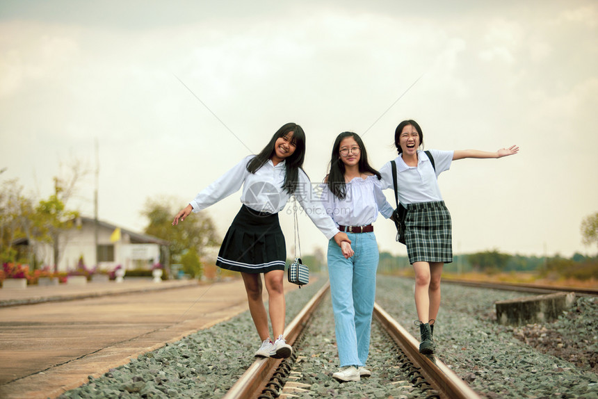 旅行三名亚裔青少年在铁路赛道上玩乐美丽旅游图片