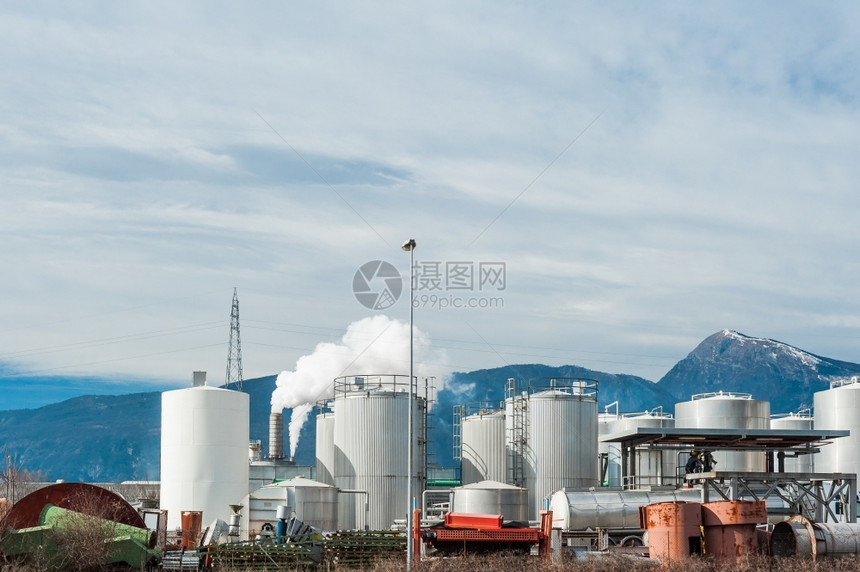 烟雾活动蓝色的意大利阿尔卑斯山背景下一个家具工厂的业在意大利阿尔卑斯山的背景下有吸烟囱图片