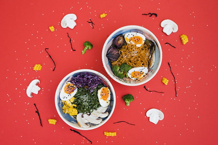 最佳机器辣拉面碗和条煮鸡蛋蔬菜配有海草沙拉红背景水果图片