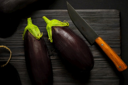 成熟切片黑色的木菜板上带刀茄子木制菜板上带刀的紫色茄子图片