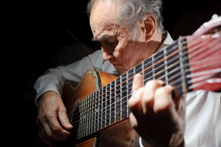 手高级的一个穿白衬衫老人弹着声音吉他黑暗背景玩图片