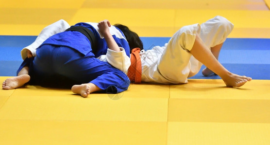 好斗的运动员锻炼和服的两名女青年在Tatami比赛中参背景