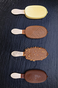 冷冻冰淇淋加粘在木棍上巧克力盖在黑石板上的巧克力酒吧小吃图片