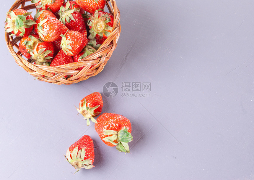 新鲜一种多汁的小篮子在紫色背景篮子和红草莓上收集的图片