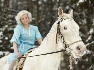 女士穿着蓝裙子的迷人女骑着白马专注在眼上乡村的爱好图片