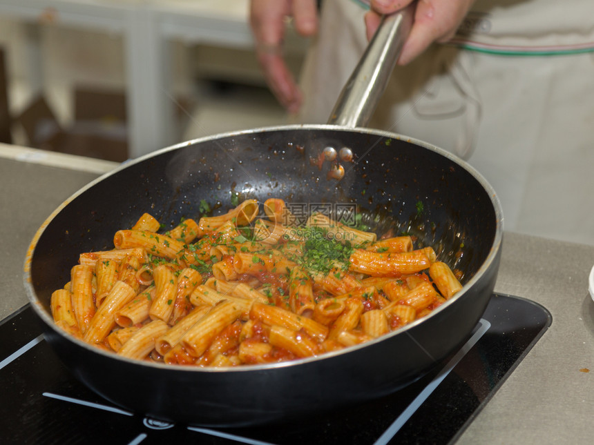 晚餐生的食谱在平底锅里煮意大利面厨师在房工作平底锅里煮意大利面图片