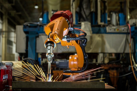 火花液压重的工业机器人在厂中焊接汽车部件图片