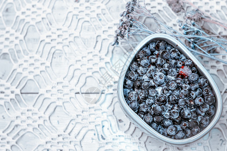 圣诞节在干鲜花和露天工作桌布空间的背景下灰色碗中新鲜的蓝莓有选择地聚焦于露天工作桌布上的蓝莓节食俄罗斯背景图片