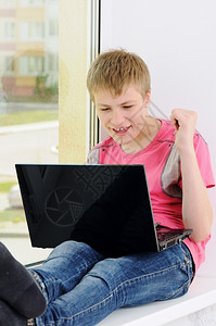 笔记本电脑带着的快乐少年坐在窗户上边坐着美丽的笔记本图片