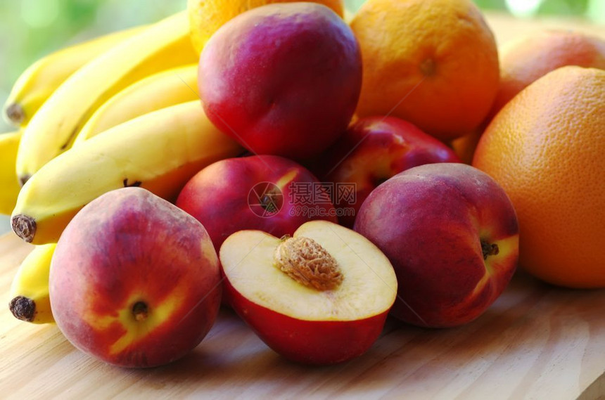 黄色的农业桌上有成熟的桃香蕉和柑橘水果抗氧化剂图片