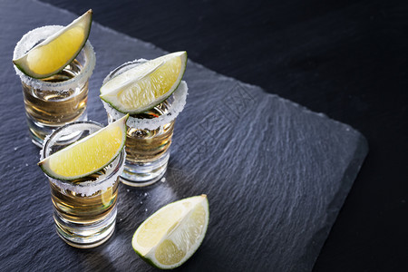 食物酸橙饮料含盐的龙舌兰酒杯和黑底色本加盐和石灰的墨西哥传统酒精鸡尾图片