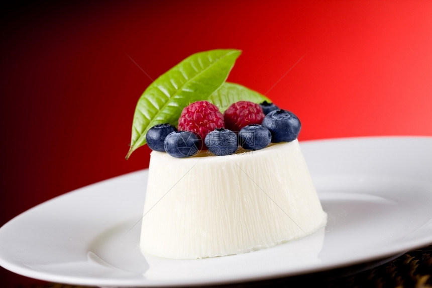 甜点奶油红背景的浆果和美味pannaCotta意大利图片