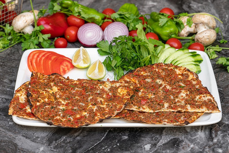 皮德香菜烹饪土耳其拉哈马昆或土耳其披萨大理石桌上有番茄鹦鹉和柠檬图片