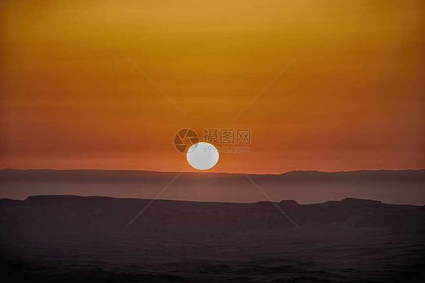 辉光黎明拉根沙暴造成天空亮橙色发光后清晨在MakteshRamonCrater上方日出图片