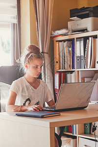 商业现代的复制在家工作使用便携式计算机坐在家庭办公室桌前的年轻妇女Candid人真实时刻情况等背景图片