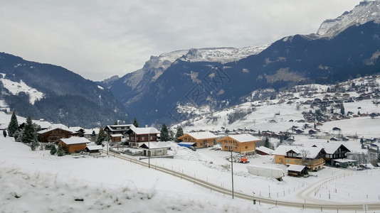 爬坡道山丘上的村落和美丽景色覆盖着冬季雪的山峰瑞士丘陵蓝色的图片