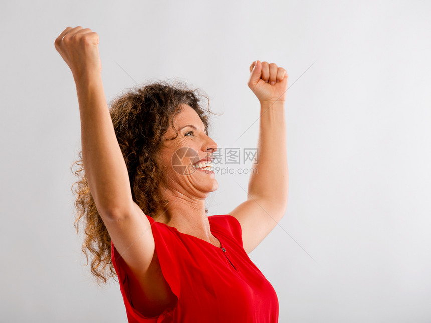 一个快乐的中年黑发女人肖像手举起来表示胜利优者愉快自信的图片