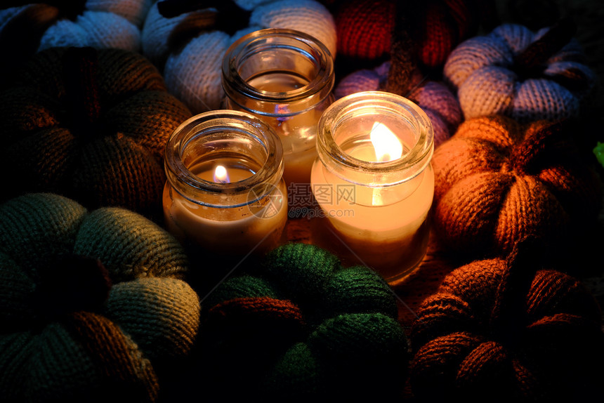 美丽的编织南瓜来自有三根蜡烛的缝线夜间三根蜡烛光造就了丰富多彩的背景休闲活动制作的精美手工产品自制针织的假期图片