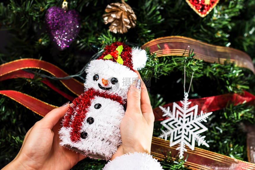手握着圣诞雪人雕像在圣诞树前的装饰被隔离的fir树乐趣丰富多彩的季节图片