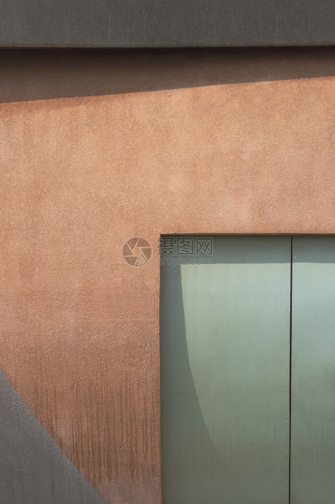 建筑学崎岖以曲线形状装饰风格的当代建筑棕色和灰粗水泥墙上的绿色铁门前视面钢优质的图片