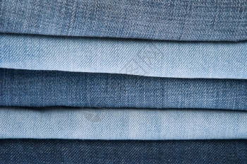 折叠蓝色牛仔裤堆背景或纹理牛仔布衣柜图片