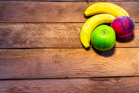 新鲜的异国情调吃木制桌上的水果混合香蕉苹果葡萄酒图片