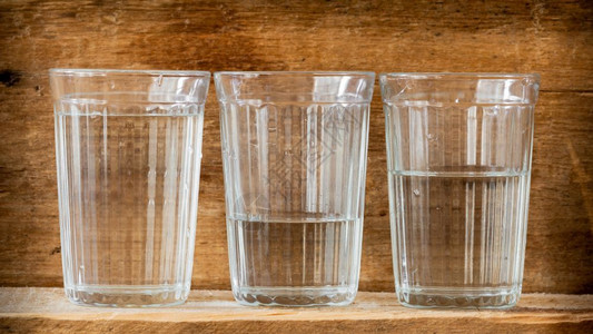 新鲜的清爽喝三杯水用自然光照亮放在木板上的三杯水高清图片