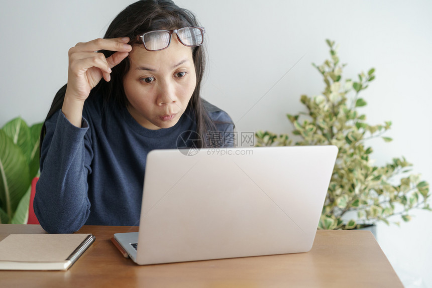 这位亚洲女在办公室的笔记本电脑上工作脸表情令人惊讶对工作成功感到高兴肖像女士年轻的图片