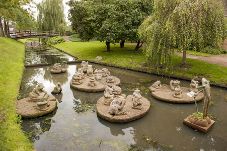 在一座城市公园池塘中雕塑青蛙乐团玩坐草图片