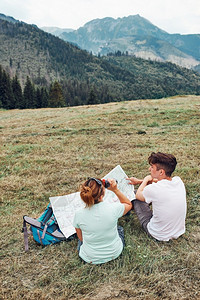 白种人一家在山区度假旅行期间坐在草地上查看山区试验人们在山上度假期间积极地在户外度过时间女士部背景图片