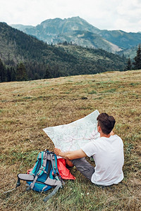 青少年场地一家人在山区度假旅行期间坐在草地上查看山区试验人们在山上度假期间积极地在户外度过时间坐着背景图片