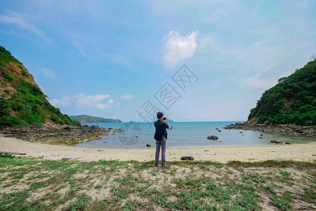 假期景观年轻亚洲摄影师在海滩上用照相机拍水图片