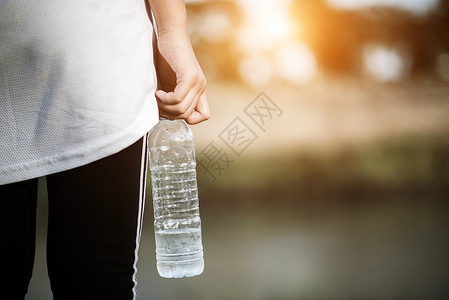 女白色的年青健身女在运动后手持水瓶自然背景