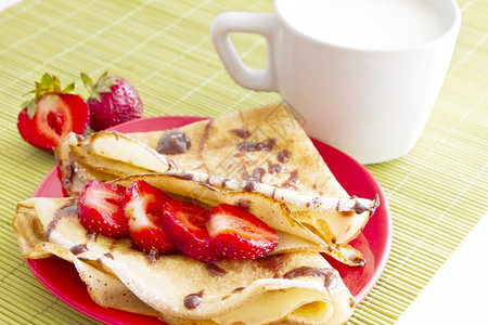 新鲜的甜点金煎饼草莓和白底牛奶杯背景图片