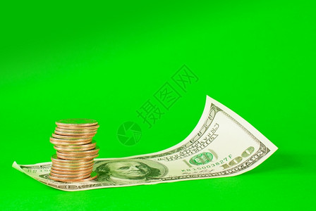滚动商业堆积在铁条叠的硬币铺在一10美元的钞票上超过绿色背景贷款图片