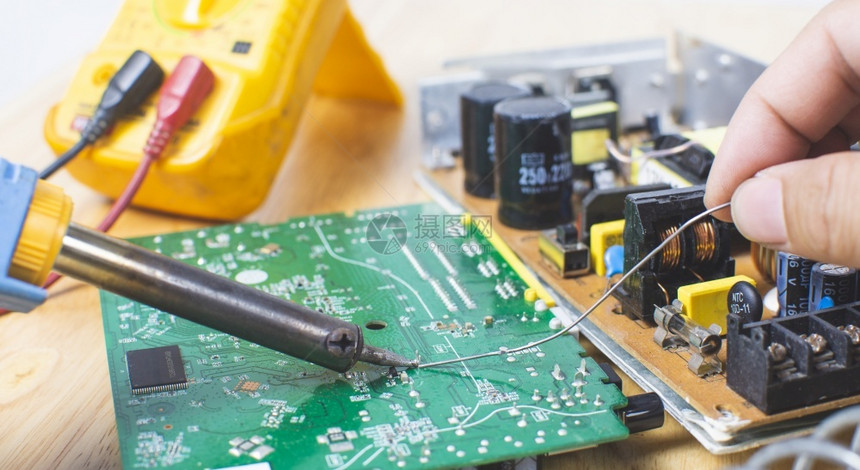 电子技术员正在使用电焊接铁来修理电子路板图片