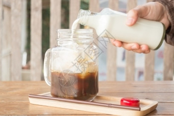 手瓶子挤牛奶到冰的咖啡杯股票照片糖高清图片