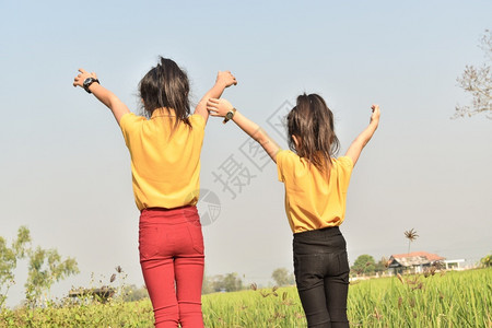 户外笑提高两个女孩在田地里双手举起高到天上图片