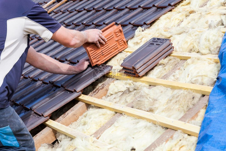 木头防水的工人屋顶上铺瓷砖的图片