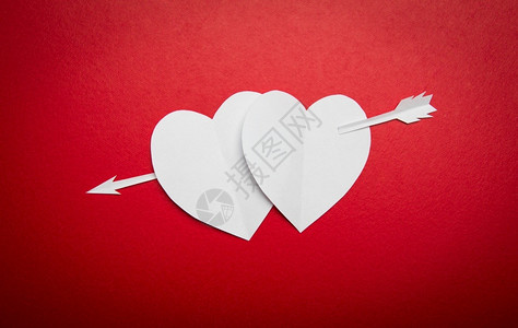 快乐的象征为了两个纸面红心穿透了情人节的箭头符号并复制文本或设计空间图片