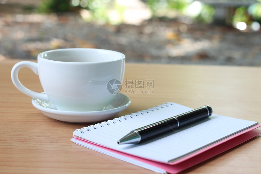 咖啡杯和笔记本放在桌上图片